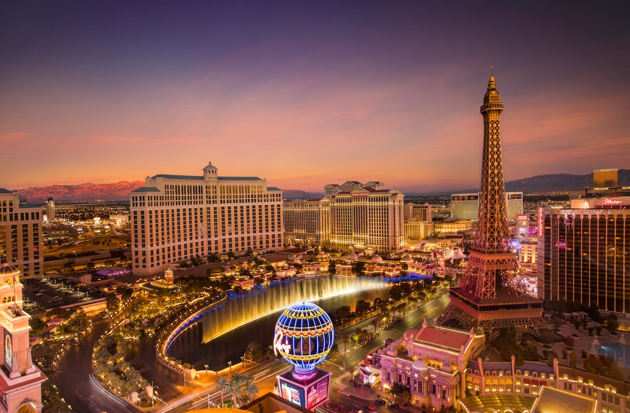 Stunning aerial view of Las Vegas skyline at sunset, featuring the Eiffel Tower and Bellagio fountains.